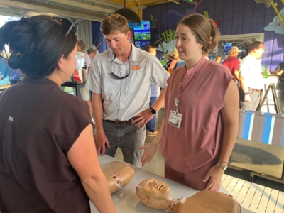 Volunteers stand in front of CPR training mannequins.